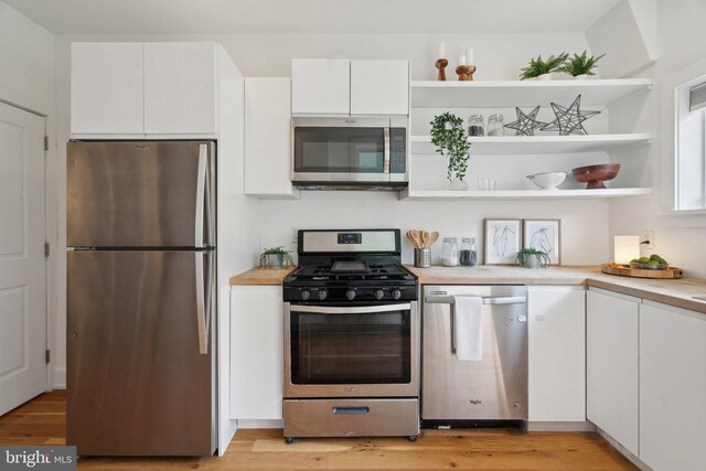 kitchen featuring light wood-type flooring, sink, stainless steel appliances, and white cabinets