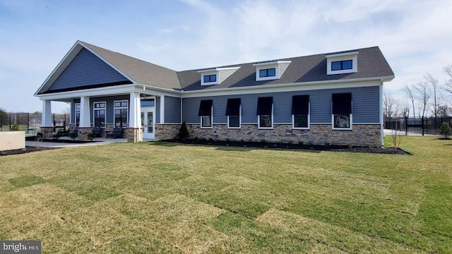 craftsman house featuring stone siding, fence, a front lawn, and french doors