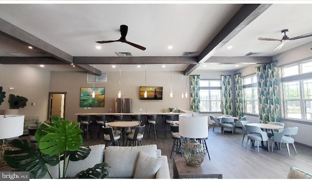 interior space with ceiling fan, beamed ceiling, wood finished floors, and visible vents