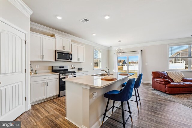 kitchen with a kitchen island with sink, a fireplace with flush hearth, visible vents, a sink, and stainless steel fridge with ice dispenser