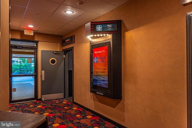 hall featuring a paneled ceiling and carpet floors