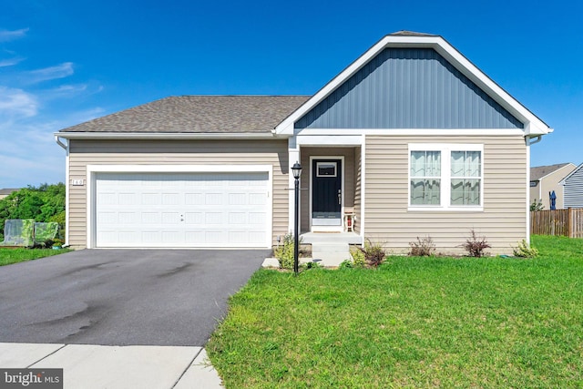 ranch-style home with driveway, a garage, a shingled roof, fence, and a front yard