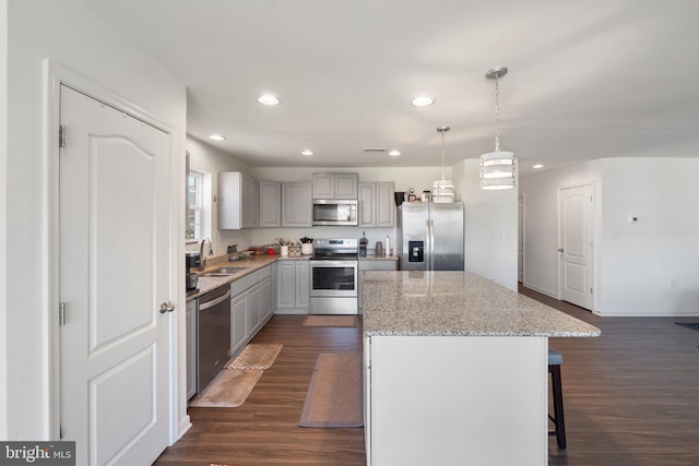 kitchen with dark wood-style floors, stainless steel appliances, recessed lighting, a kitchen island, and a kitchen bar