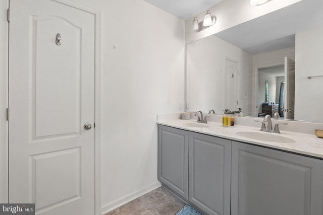 full bath with double vanity, a sink, and baseboards