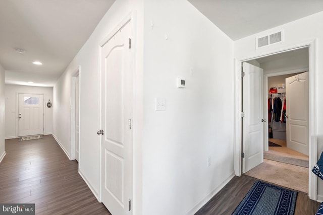 corridor featuring dark wood-style floors, recessed lighting, visible vents, and baseboards