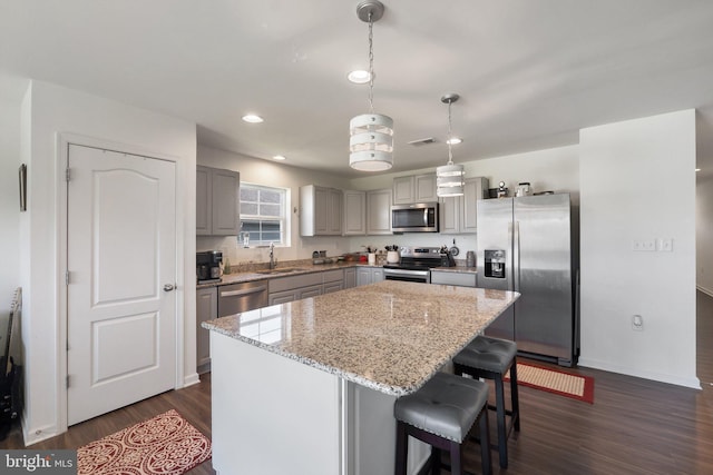 kitchen with gray cabinetry, a center island, stainless steel appliances, dark hardwood / wood-style flooring, and pendant lighting