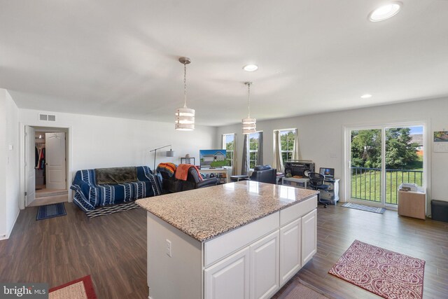 kitchen featuring white cabinetry, decorative light fixtures, dark hardwood / wood-style flooring, a kitchen island, and light stone countertops