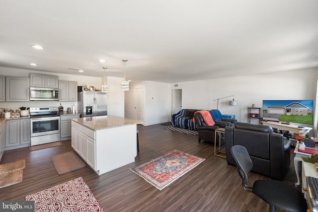 kitchen with appliances with stainless steel finishes, open floor plan, a kitchen island, and dark wood-style flooring