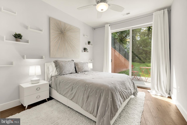 bedroom with visible vents, multiple windows, wood finished floors, and access to outside