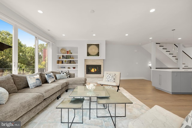 living room featuring light wood finished floors, stairway, recessed lighting, and a tiled fireplace