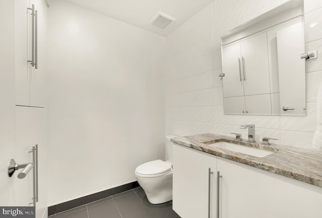 bathroom featuring visible vents, toilet, tile walls, tile patterned flooring, and vanity