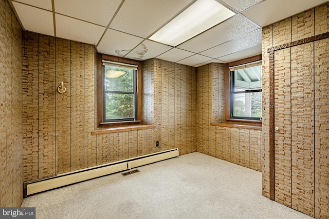 spare room with wood walls, a baseboard radiator, a paneled ceiling, and carpet flooring