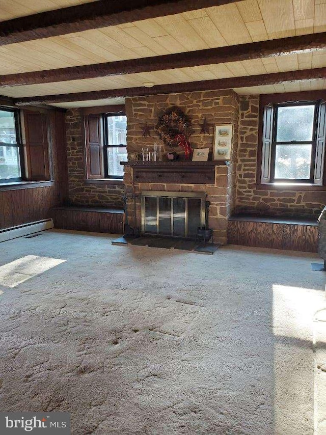 unfurnished living room with carpet floors, wood walls, a fireplace, and beam ceiling