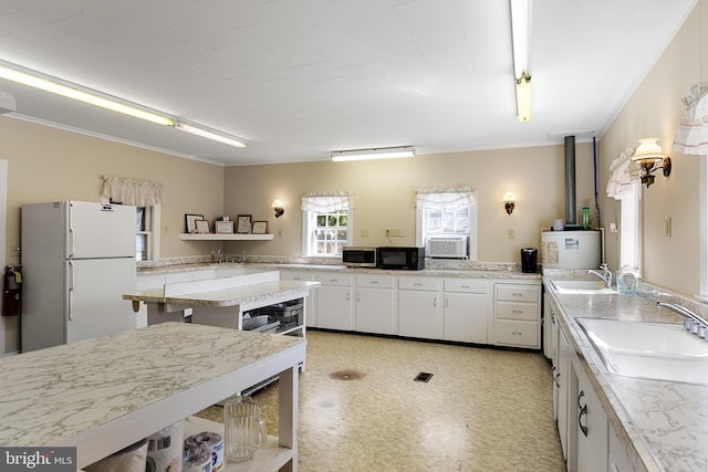 kitchen featuring white refrigerator, ornamental molding, white cabinetry, and sink