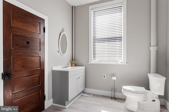 bathroom with a wealth of natural light, vanity, toilet, and hardwood / wood-style flooring