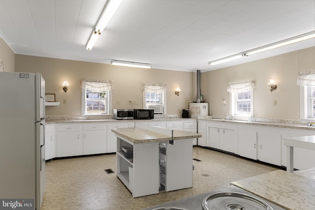 kitchen with white refrigerator, plenty of natural light, and white cabinetry