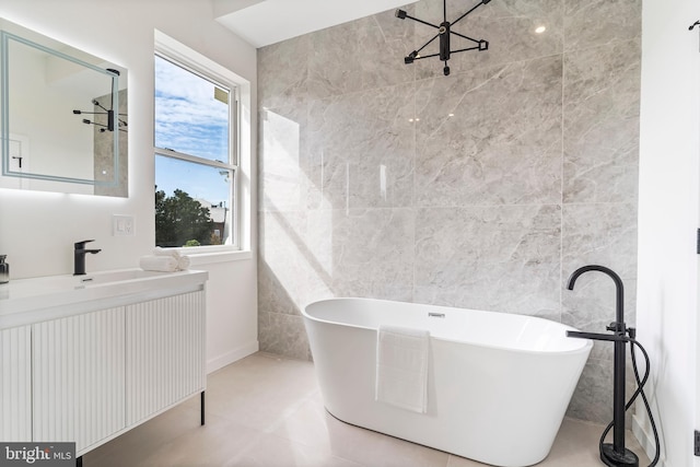 bathroom with plenty of natural light, a tub, vanity, and tile walls