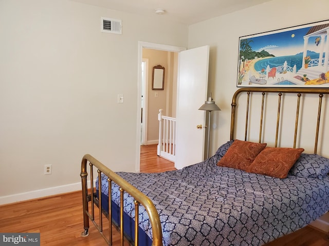 bedroom with baseboards, wood finished floors, and visible vents