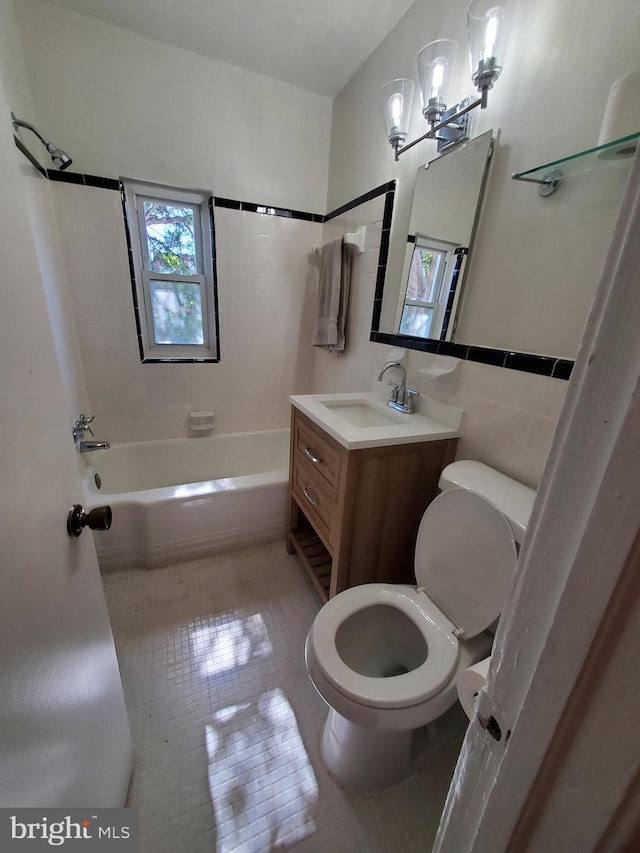 full bathroom with bathtub / shower combination, tile walls, tile patterned flooring, vanity, and toilet