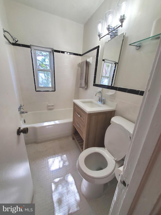 full bathroom with a healthy amount of sunlight, toilet, tile patterned flooring, and tile walls