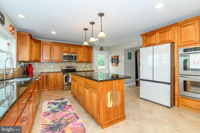 kitchen with dark stone countertops, sink, a center island, and appliances with stainless steel finishes