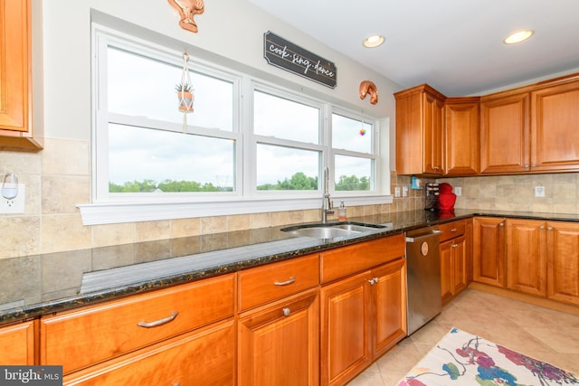 kitchen featuring light tile patterned floors, sink, dishwasher, tasteful backsplash, and dark stone counters