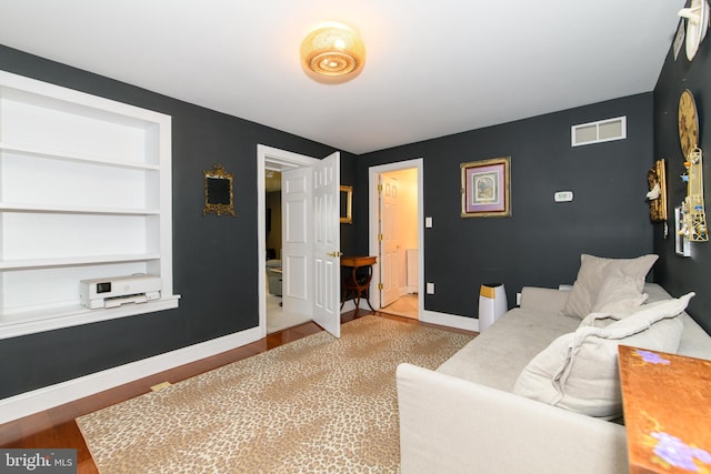 living room with built in shelves and hardwood / wood-style flooring