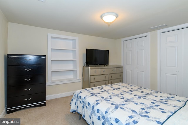 bedroom with light carpet and two closets