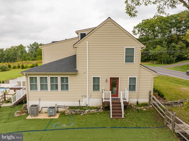 rear view of house with cooling unit, a yard, and a patio area