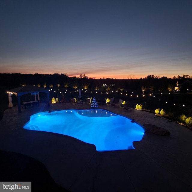 pool at dusk with a patio area