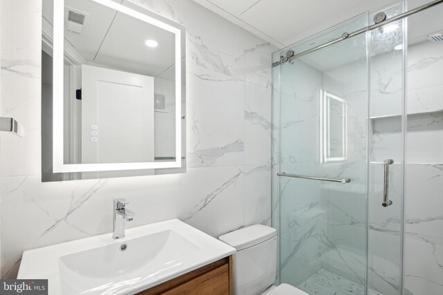 bathroom featuring vanity, toilet, tile walls, and a shower with shower door