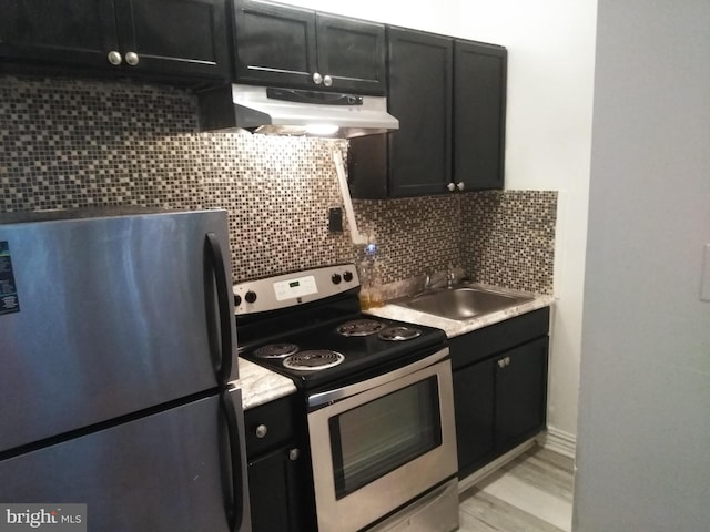 kitchen featuring appliances with stainless steel finishes, light wood-type flooring, tasteful backsplash, and sink