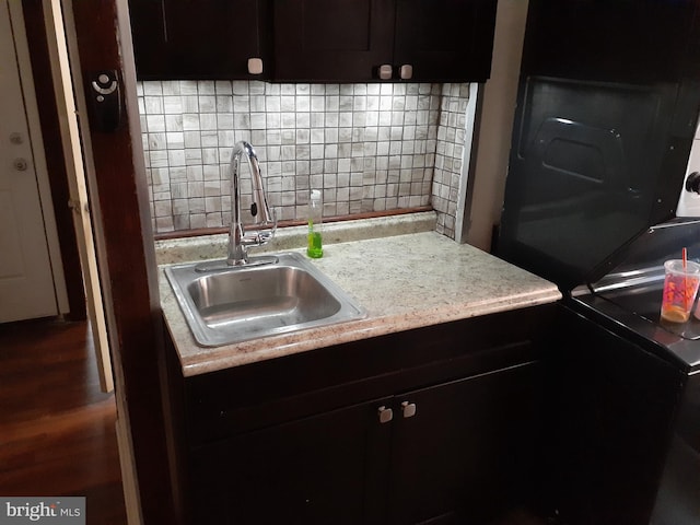 kitchen with backsplash, dark brown cabinetry, sink, and dark wood-type flooring