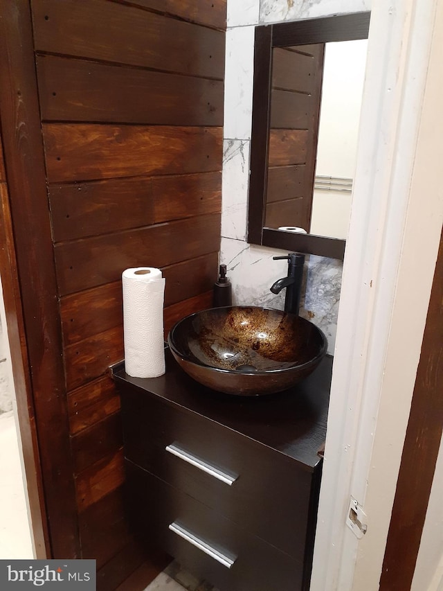 bathroom featuring wooden walls and sink