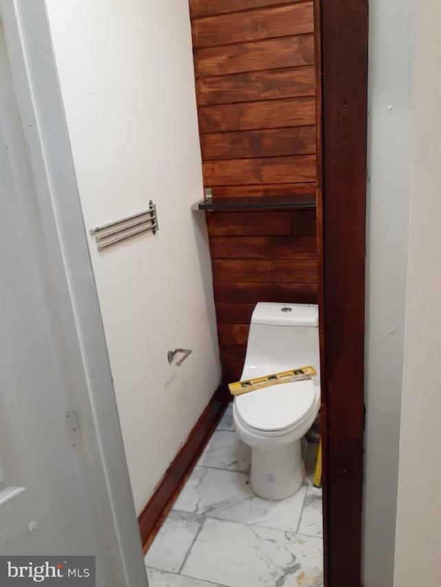 bathroom featuring toilet and wooden walls