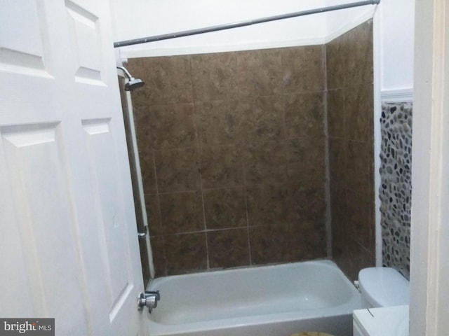 bathroom with toilet and tiled shower / bath