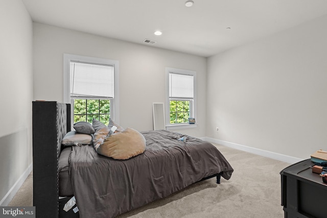 bedroom with light carpet and multiple windows