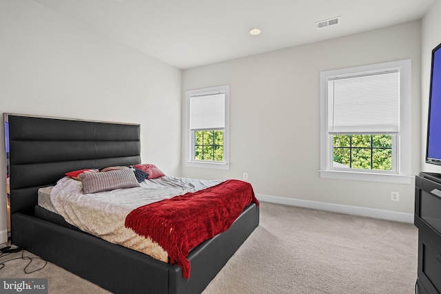 bedroom featuring light carpet and multiple windows