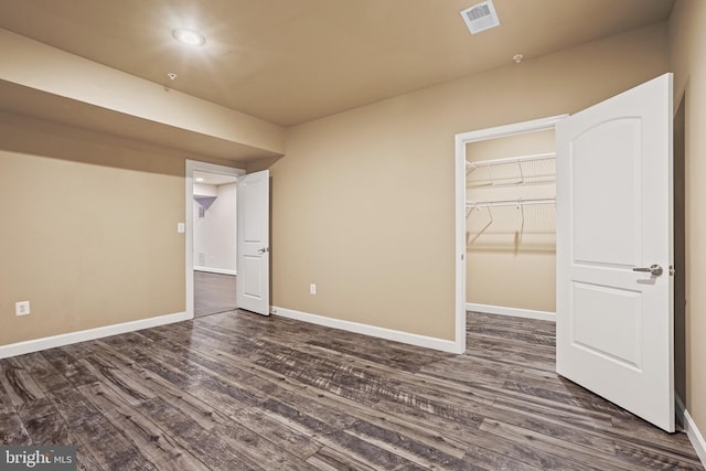 unfurnished bedroom with a walk in closet, dark hardwood / wood-style flooring, and a closet