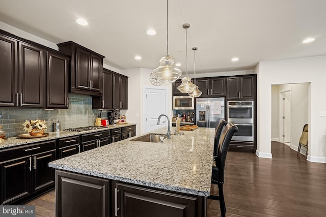 kitchen with appliances with stainless steel finishes, a breakfast bar area, a kitchen island with sink, and sink