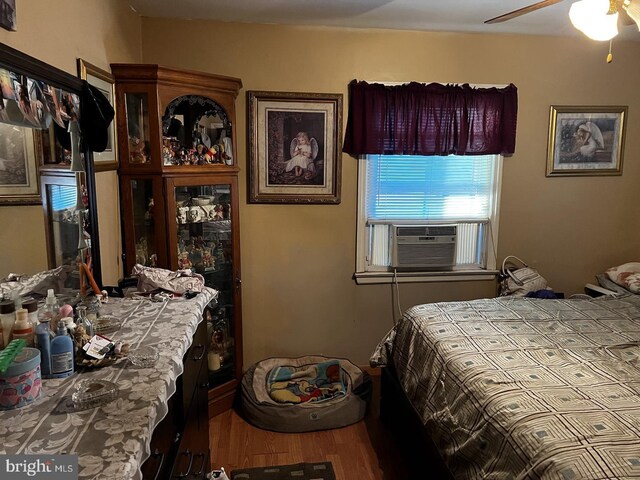 bedroom featuring hardwood / wood-style floors, cooling unit, and ceiling fan