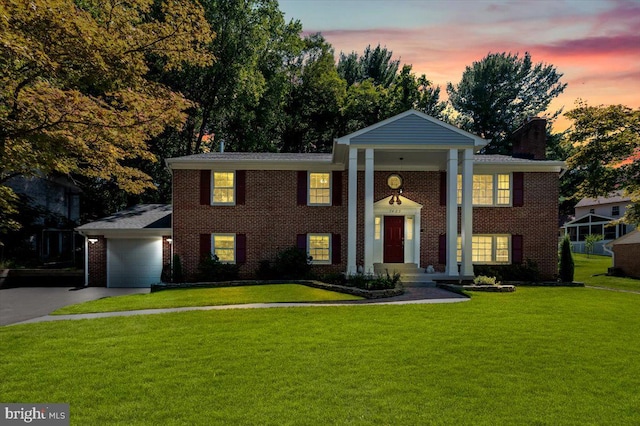 neoclassical home featuring a lawn and a garage