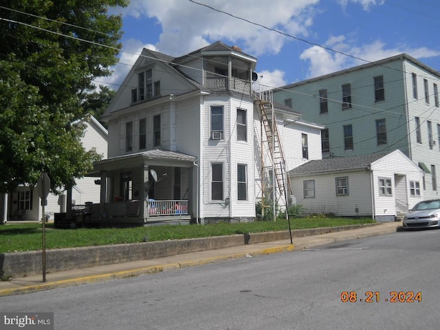 view of front facade featuring cooling unit, a porch, and a balcony