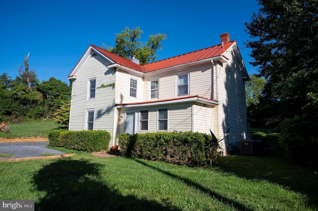 view of front of home with cooling unit and a front yard