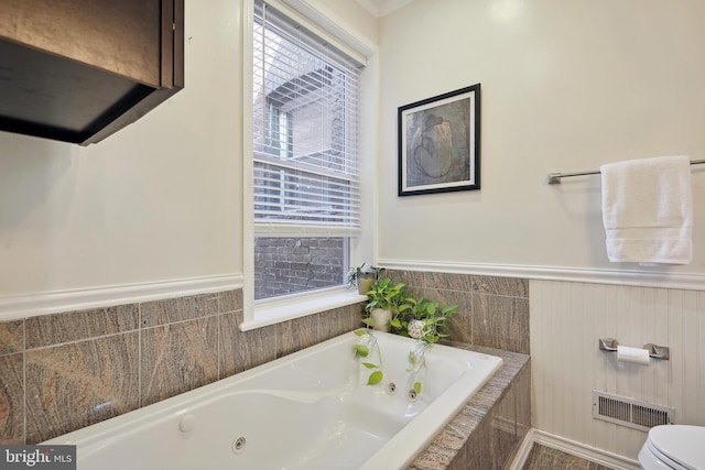 bathroom with toilet and tiled bath