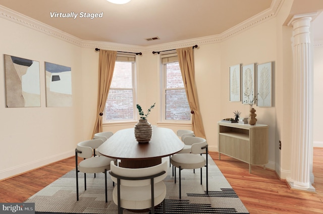 dining room featuring crown molding, ornate columns, and light hardwood / wood-style floors