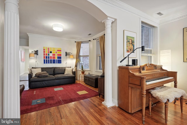 living room featuring dark wood-type flooring, ornamental molding, and decorative columns