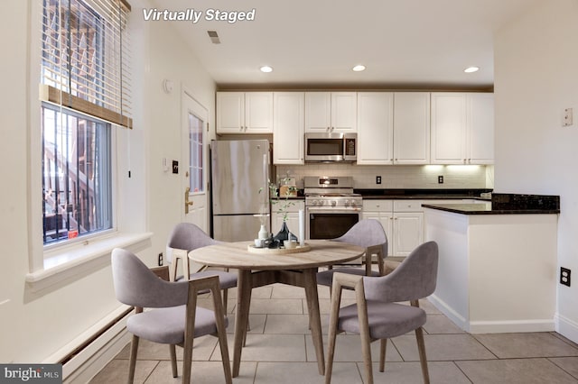 kitchen with appliances with stainless steel finishes, white cabinetry, and a wealth of natural light