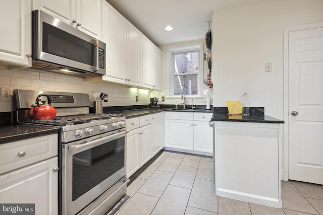 kitchen with sink, light tile patterned flooring, stainless steel appliances, and white cabinets