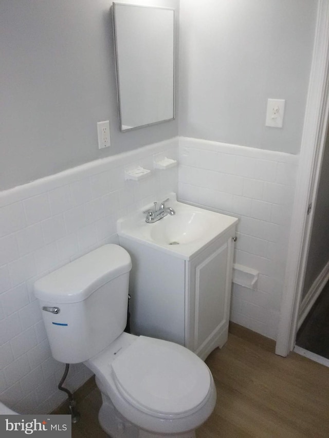 bathroom featuring vanity, toilet, hardwood / wood-style floors, and tile walls